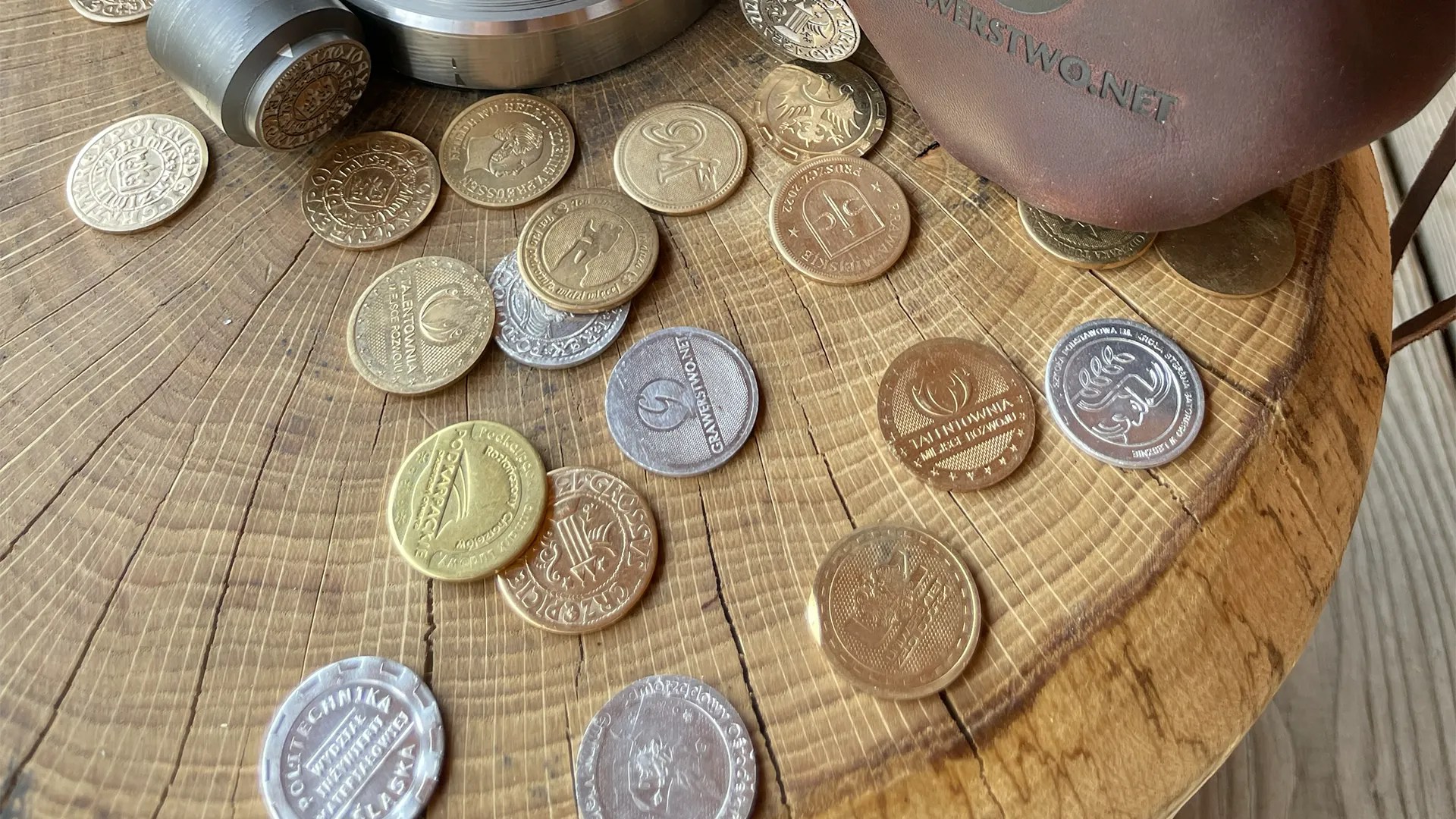 Zbliżenie na monety pamiątkowe wybite przez Mennicę Eventową, leżące na drewnianym pniu