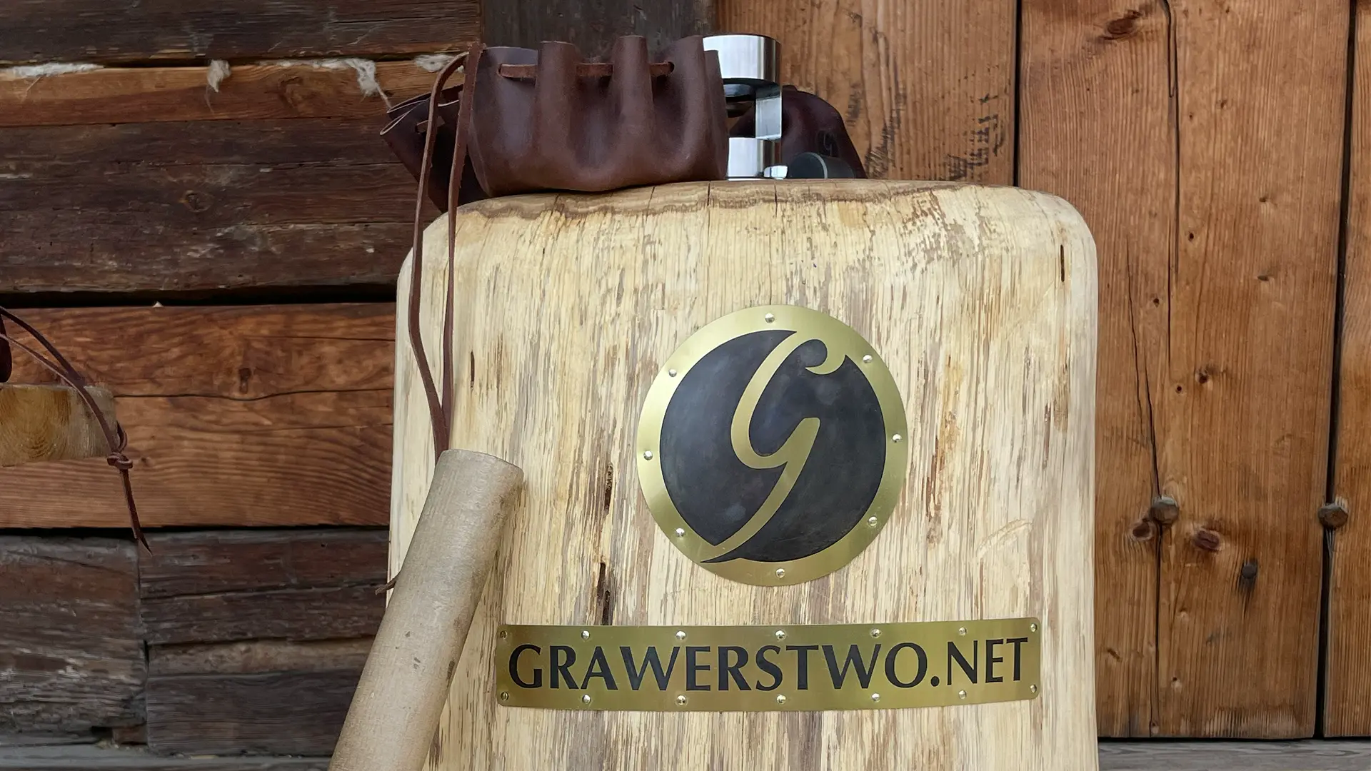 Urządzenie do wybijania monet z logo Grawerstwo.net na tle drewnianej ściany
